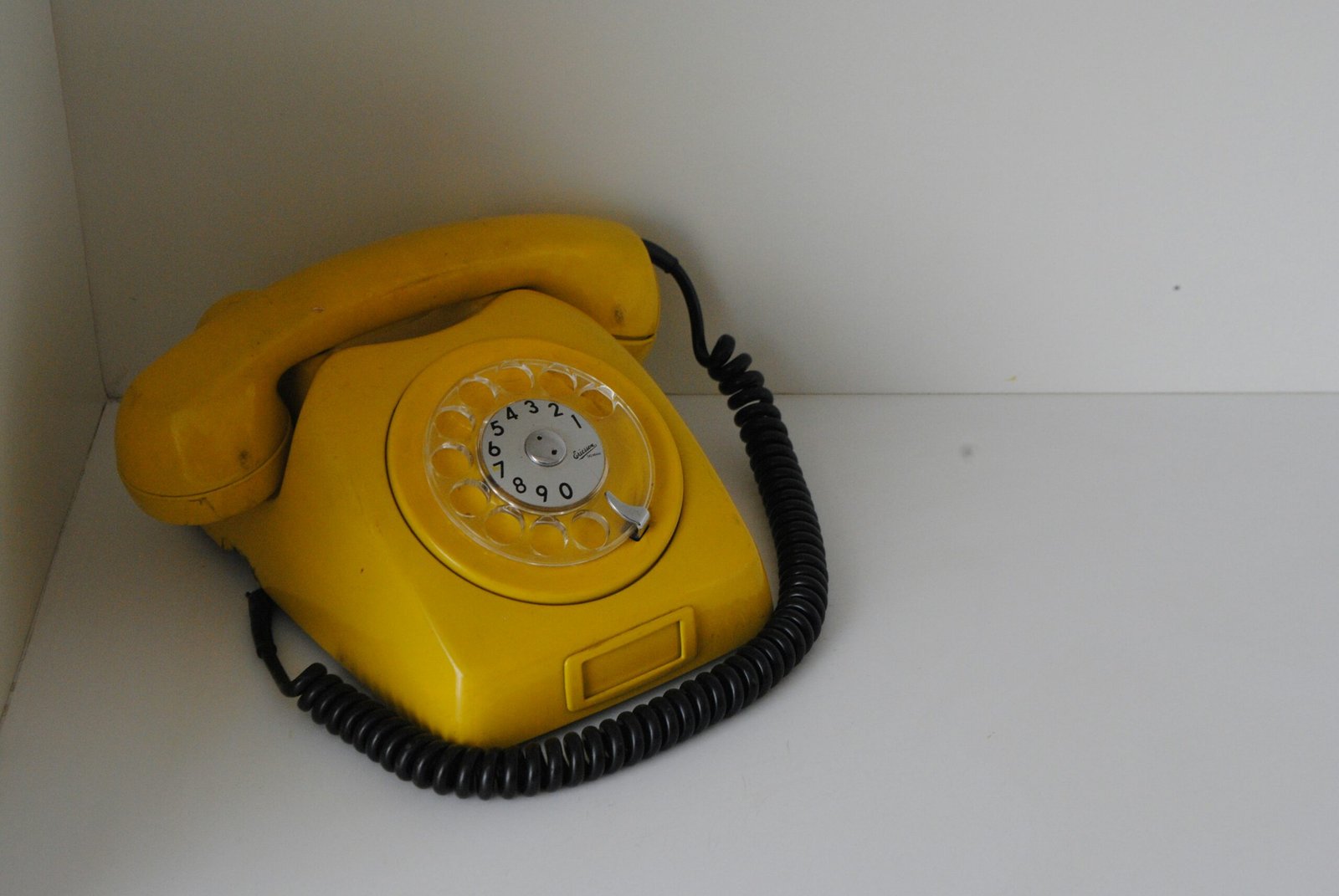 A yellow telephone sitting on top of a white counter